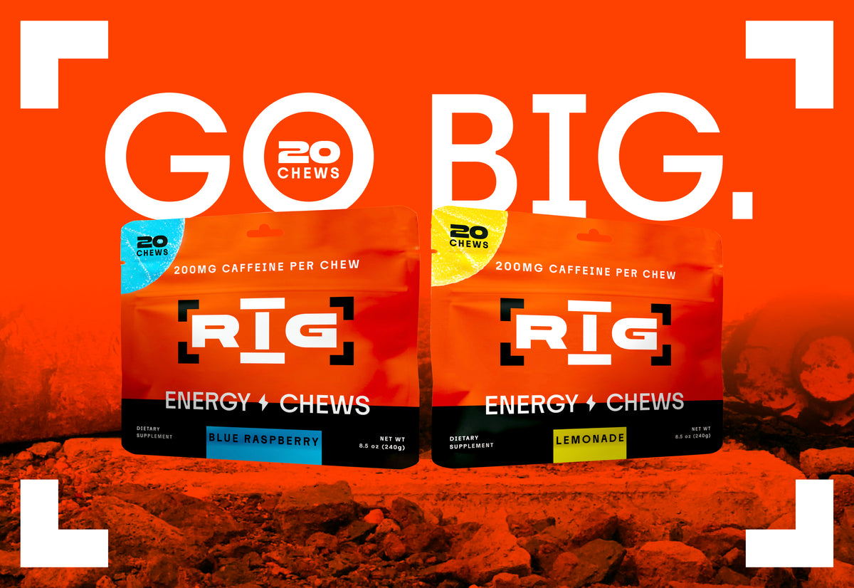 Two bags of RIG Energy Chews by 20 Chews are displayed against a vibrant orange background with a rocky texture. The left bag is Blue Raspberry and the right bag is Lemonade, both featuring bright orange packaging with black and white text.